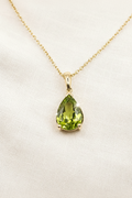 A natural pear-like peridot gemstone encased in a golden frame laced together with a golden necklace by Ophelisse.