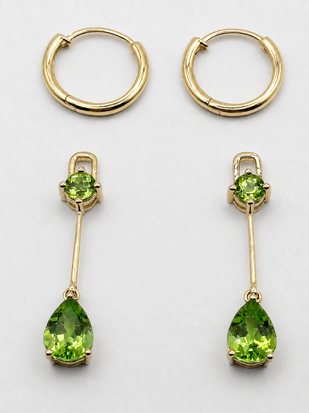A pair of gold huggie hoop earrings and a pair of gold drop earrings with round and pear cut natural green peridot gemstones, by Ophelisse