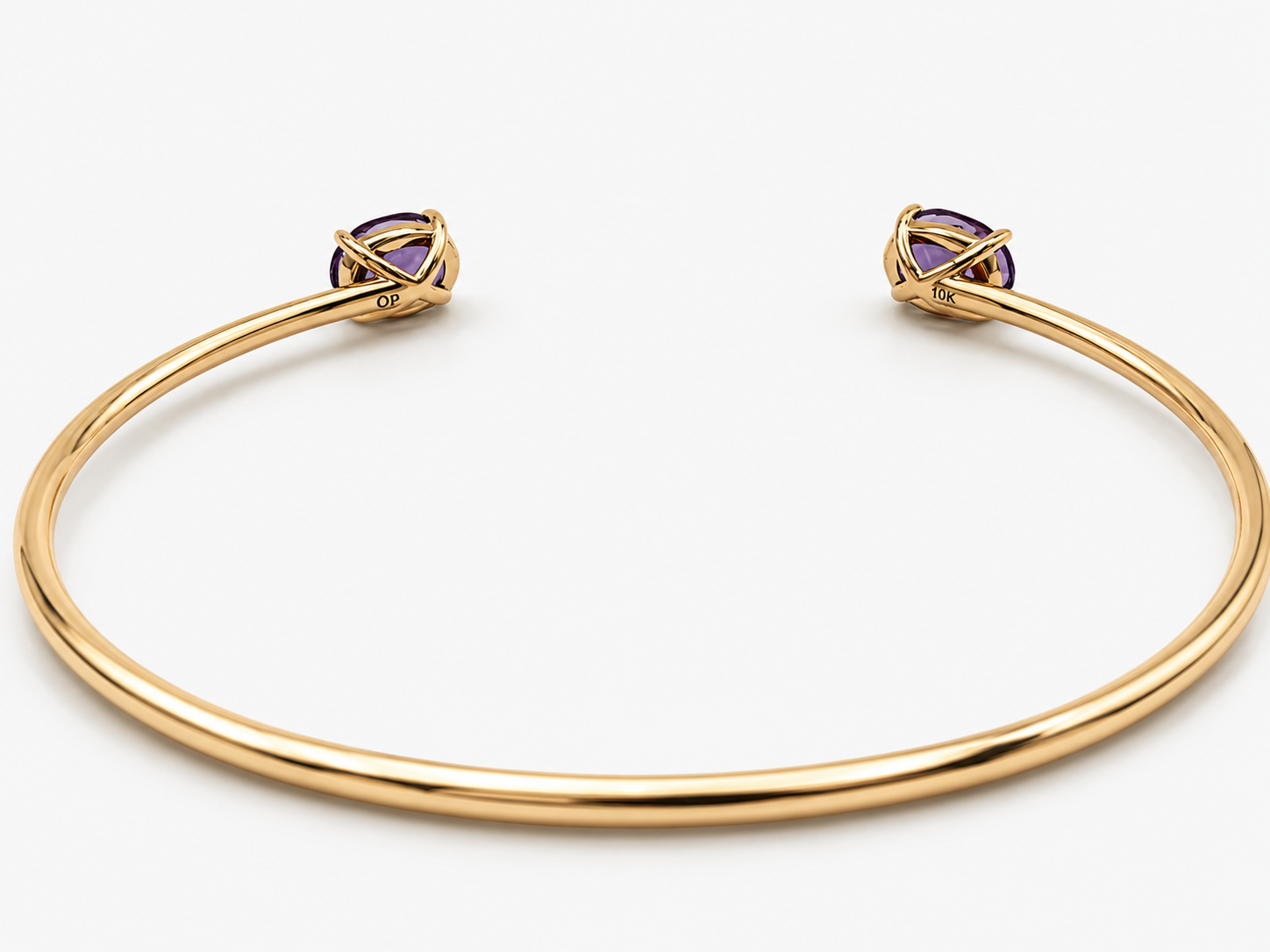 A solid 10k yellow gold open cuff bangle bracelet with two oval amethyst gemstone accents at the ends by Ophelisse, shown on a clean white background, laying flat showing the bottom of the natural amethyst stones, 10k mark, and Ophelisse stamp