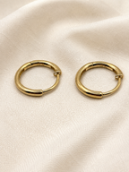 A pair of solid 10k yellow gold dangle earring hoop displayed on a textured, off-white fabric background. Trademarked 10k by Ophelisse.