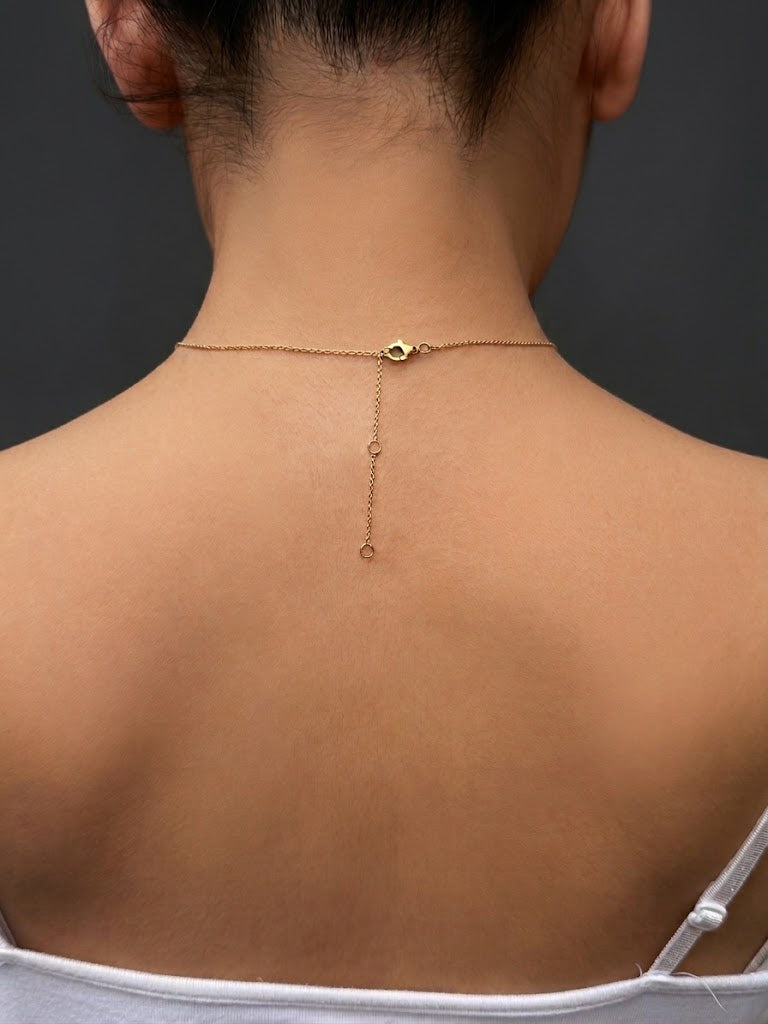 A close-up back view of a real model wearing a solid 10k yellow gold chain necklace with adjustable length of 16, 18, or 20 inches.