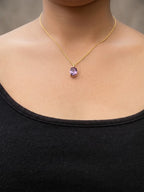 A close-up of a model wearing Ophelisse solid 10k gold chain necklace with an oval purple natural amethyst gemstone pendant at 16 inch in length .