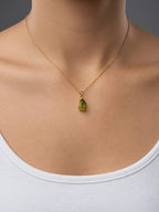 A real model wearing Ophelisse solid 10k gold chain necklace with a pear-shaped natural green peridot gemstone pendant, at 16-inch.