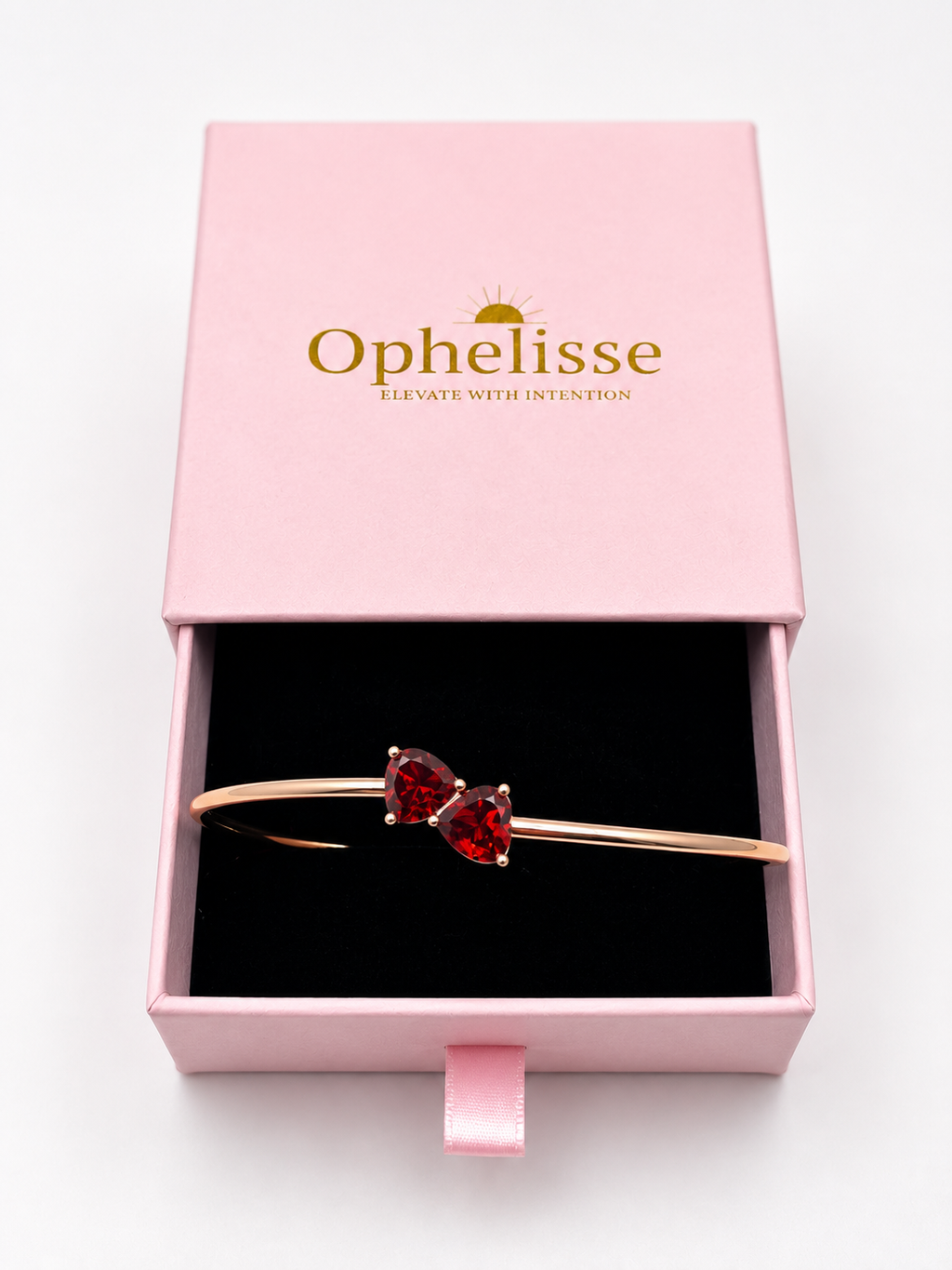 A solid 10k rose gold cuff bracelet with two heart-shaped natural red garnet gemstones, presented inside an open pink Ophelisse gift box with a black interior.