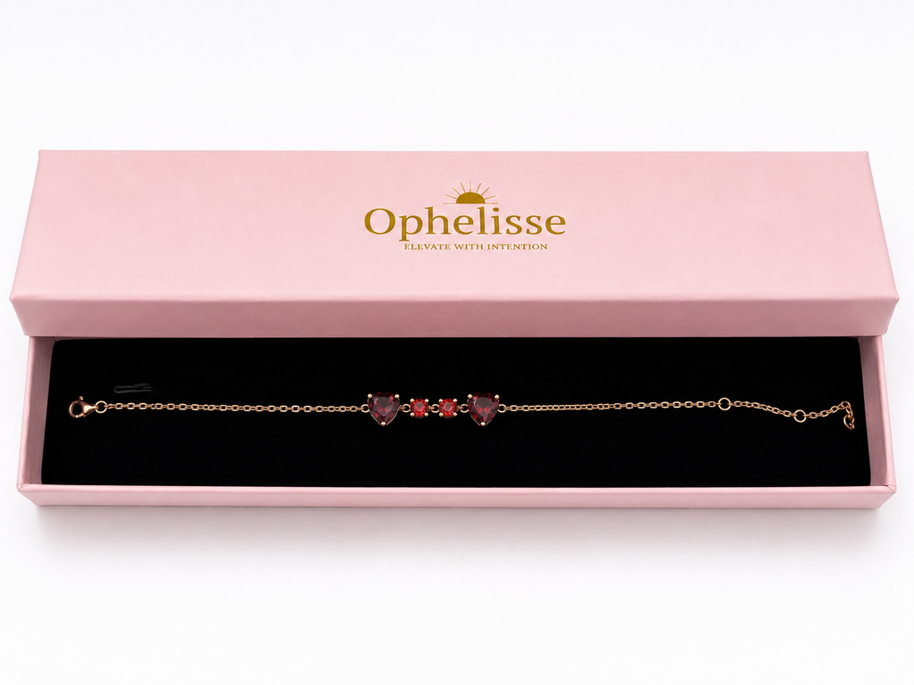 A solid 10k rose gold chain bracelet with two natural red heart-shaped and two round-shaped garnet gemstones, presented in an open pink Ophelisse jewelry box with a black velvet interior.
