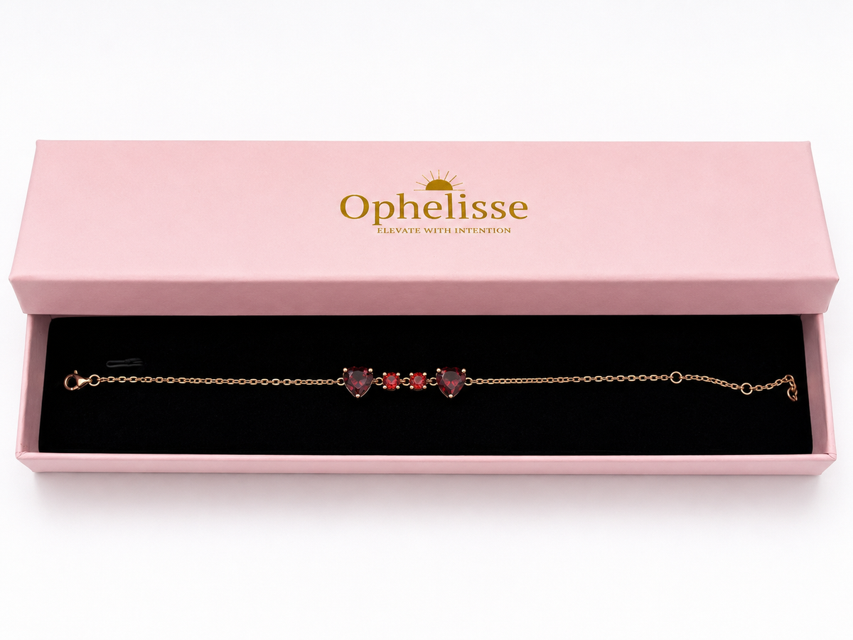A solid 10k rose gold chain bracelet with two natural red heart-shaped and two round-shaped garnet gemstones, presented in an open pink Ophelisse jewelry box with a black velvet interior.