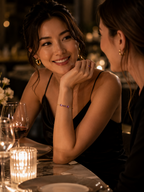 A woman in a black dress smiles at a dinner get together with another woman, she looks stunning with a solid 10k yellow gold natural amethyst bracelet chain by Ophelisse on her wrist.