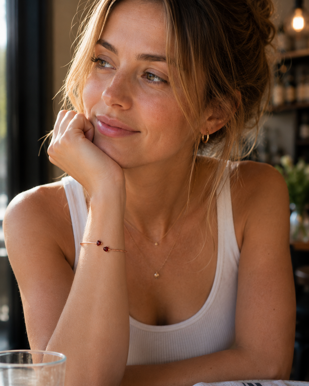 A woman wearing Ophelisse bangle on her wrist, featuring solid 10k rose gold with two heart-shaped natural red garnet gemstones.