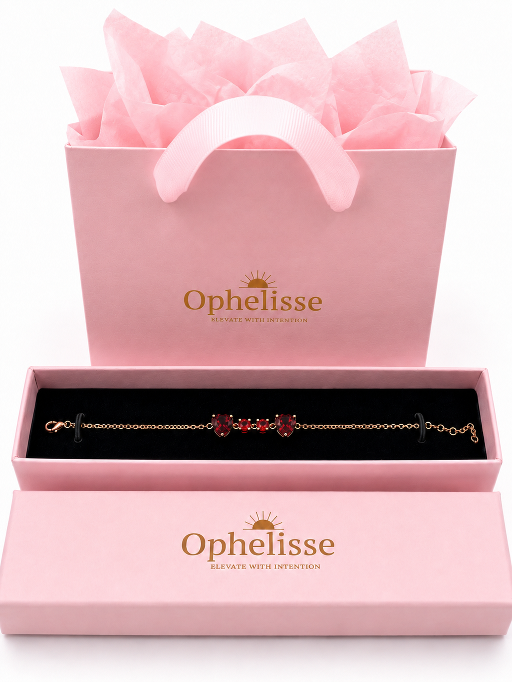 A solid 10k rose gold chain bracelet with natural red garnet gemstones displayed in an open pink Ophelisse presentation box, with a matching pink gift bag filled with tissue paper behind it on a white background.