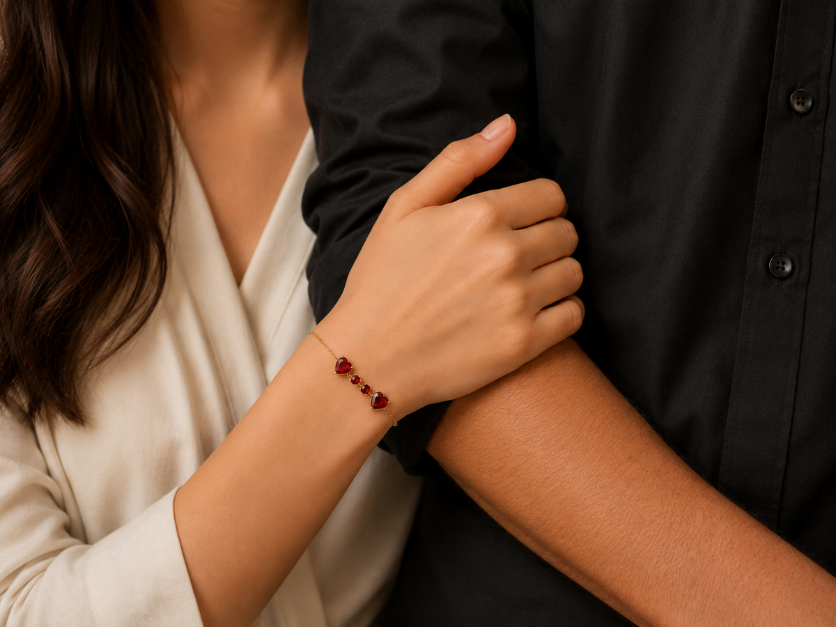 Close-up lifestyle photo of Ophelisse solid 10k rose gold on wrist, featured two heart-shaped and two small round-shaped natural red garnet gemstones, people holding hands, with a focus on a bracelet on one wrist.