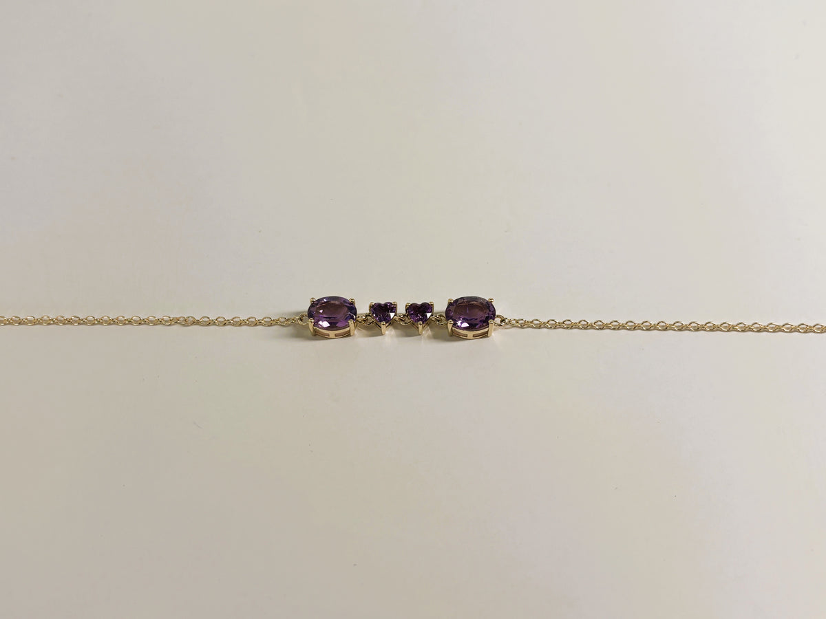 Ophelisse solid 10k yellow gold chain bracelet featuring two oval and two heart natural purple amethyst gemstones, shown closed up and side angle view against a plain off-white background.