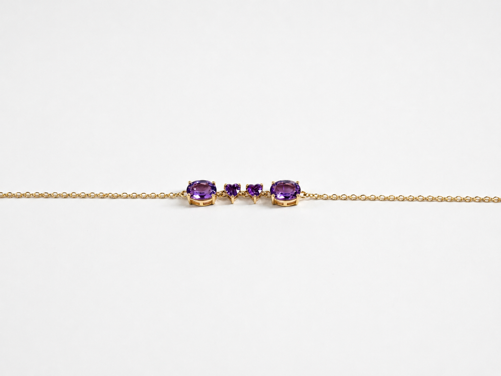 Ophelisse solid 10k yellow gold chain bracelet featuring two oval and two heart natural purple amethyst gemstones, shown closed up and side angle view against white background.
