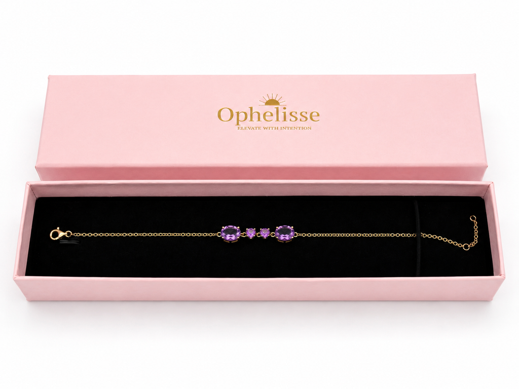A solid 10k yellow gold chain bracelet with four natural purple amethyst gemstone clusters, presented in an open pink Ophelisse jewelry box with a black velvet interior.