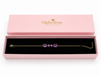 A solid 10k yellow gold chain bracelet with four natural purple amethyst gemstone clusters, presented in an open pink Ophelisse jewelry box with a black velvet interior.