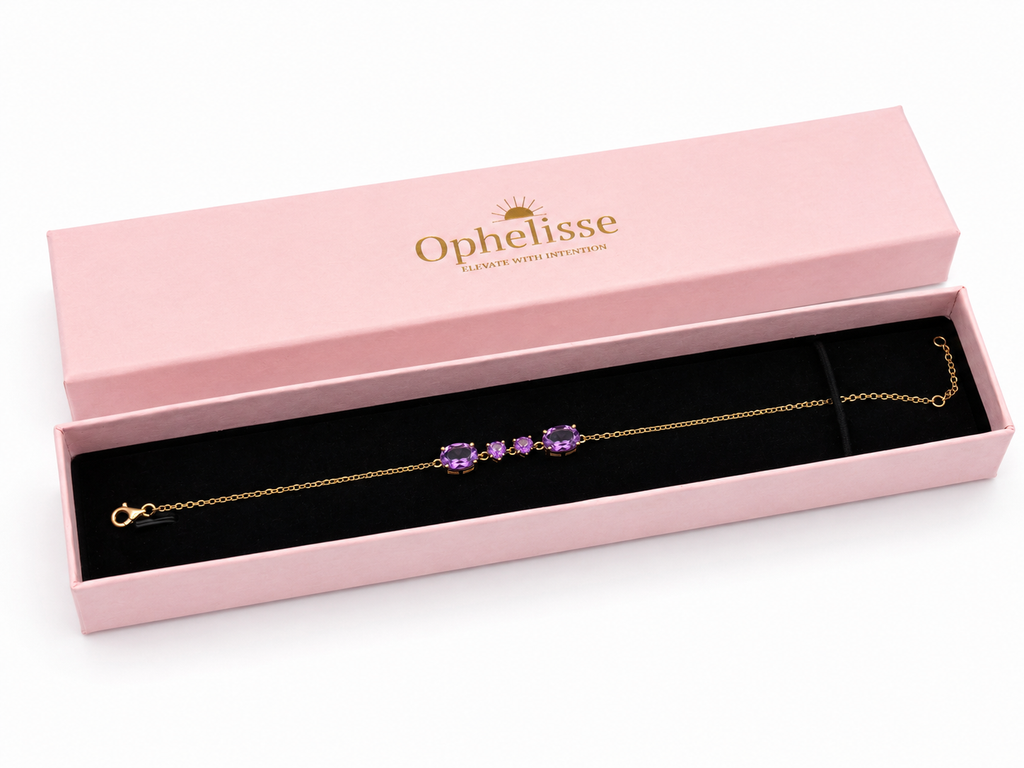 A solid 10k yellow gold chain bracelet with two oval and two heart natural amethyst purple gemstones, presented in an open pink Ophelisse gift box with a black velvet insert