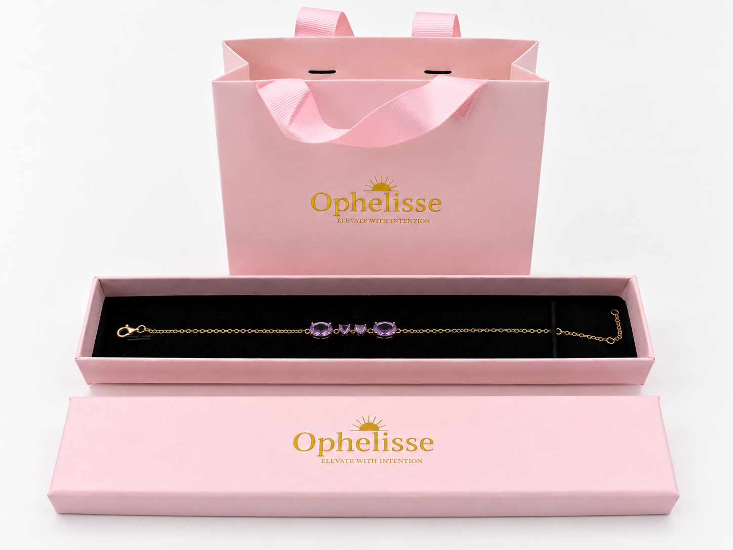 A solid 10k yellow gold chain bracelet with four natural purple amethyst gemstone accents displayed in an open pink jewelry box, with a matching pink Ophelisse shopping bag and lid behind it on a white background.