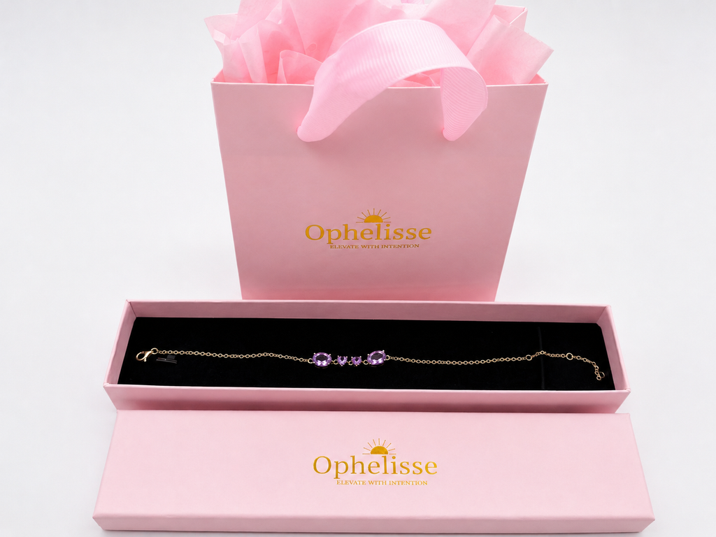 Ophelisse solid gold chain bracelet with four natural purple amethyst gemstones, presented in an open pink jewelry box with a pink shopping bag and ribbon behind it - an Ophelisse packaging experience.