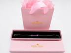 Ophelisse solid gold chain bracelet with four natural purple amethyst gemstones, presented in an open pink jewelry box with a pink shopping bag and ribbon behind it - an Ophelisse packaging experience.