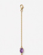 A part of a solid 10k yellow gold chain with a lobster clasp and an oval natural purple amethyst gemstone showing Ophelisse trademark, shown on a light gray background.