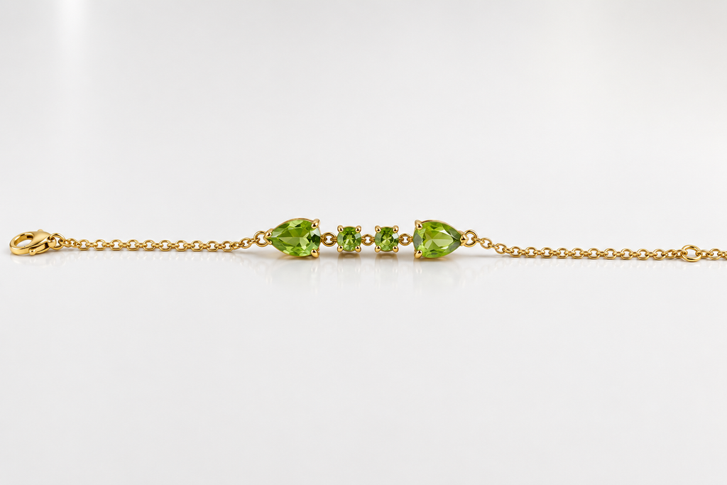 Solid 10k yellow gold bracelet chain with two pear-shaped and two round-shaped natural green peridot gemstones by Ophelisse, on a white background
