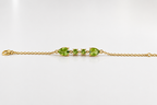 Solid 10k yellow gold bracelet chain with two pear-shaped and two round-shaped natural green peridot gemstones by Ophelisse, on a white background