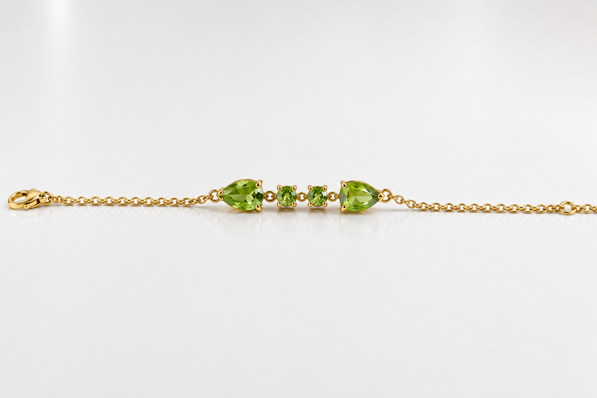 Solid 10k yellow gold bracelet chain with two pear-shaped and two round-shaped natural green peridot gemstones by Ophelisse, on a white background