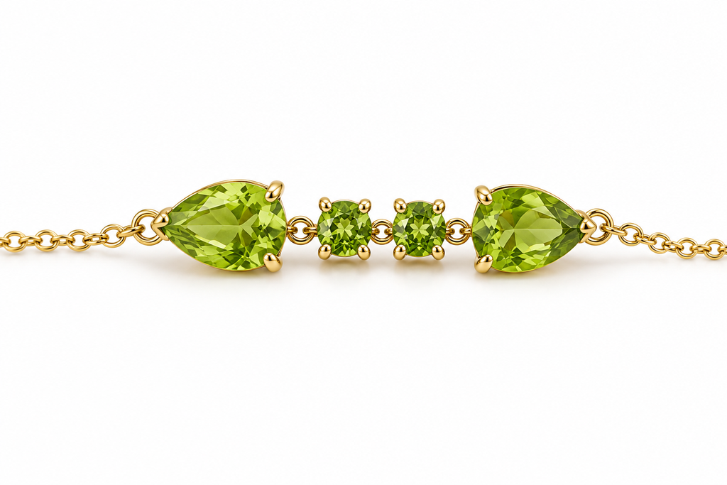 A close up view of Ophelisse solid 10k yellow gold bracelet featuring two pear-shaped and two round-shaped natural green peridot gemstones on a white background