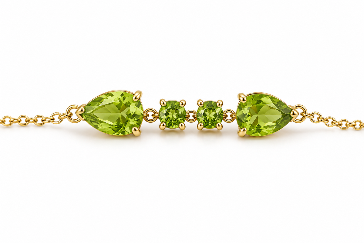 A close up view of Ophelisse solid 10k yellow gold bracelet featuring two pear-shaped and two round-shaped natural green peridot gemstones on a white background