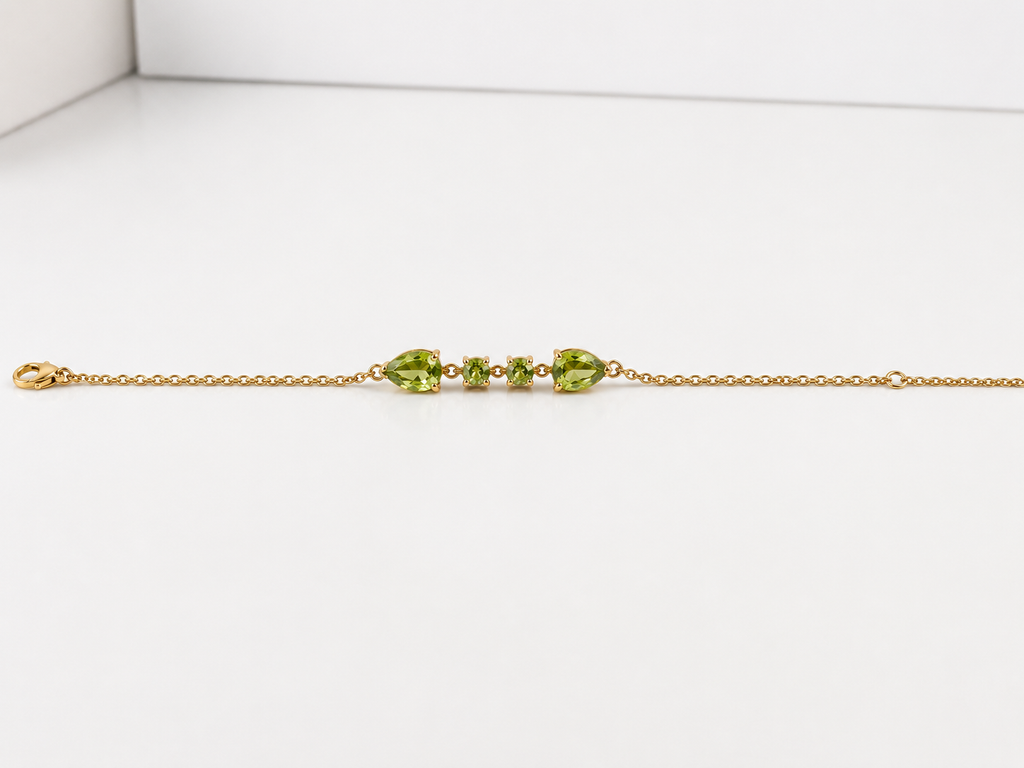 Ophelisse solid 10k yellow gold chain bracelet with natural green peridot gemstones, showing front view of two pear-shaped and two round-shaped stones, on a white background