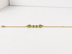 Ophelisse solid 10k yellow gold chain bracelet with natural green peridot gemstones, showing front view of two pear-shaped and two round-shaped stones, on a white background