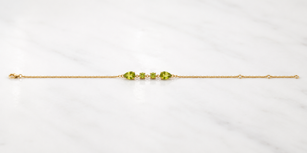 Full length view of Ophelisse solid 10k yellow gold chain bracelet with natural green peridot gemstones on a white marbled background