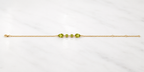 Full length view of Ophelisse solid 10k yellow gold chain bracelet with natural green peridot gemstones on a white marbled background