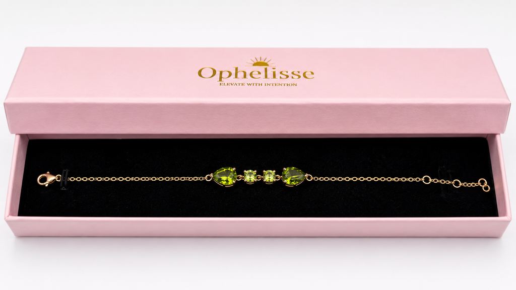 A solid 10k gold chain bracelet with natural green peridot gemstones, presented in a pink Ophelisse gift box with a black interior.