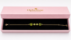 A solid 10k gold chain bracelet with natural green peridot gemstones, presented in a pink Ophelisse gift box with a black interior.