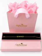 A solid 10k yellow gold chain bracelet with natural green peridot gemstone is presented in an open pink Ophelisse gift box with a black interior, in front of a pink shopping bag filled with pink tissue paper.
